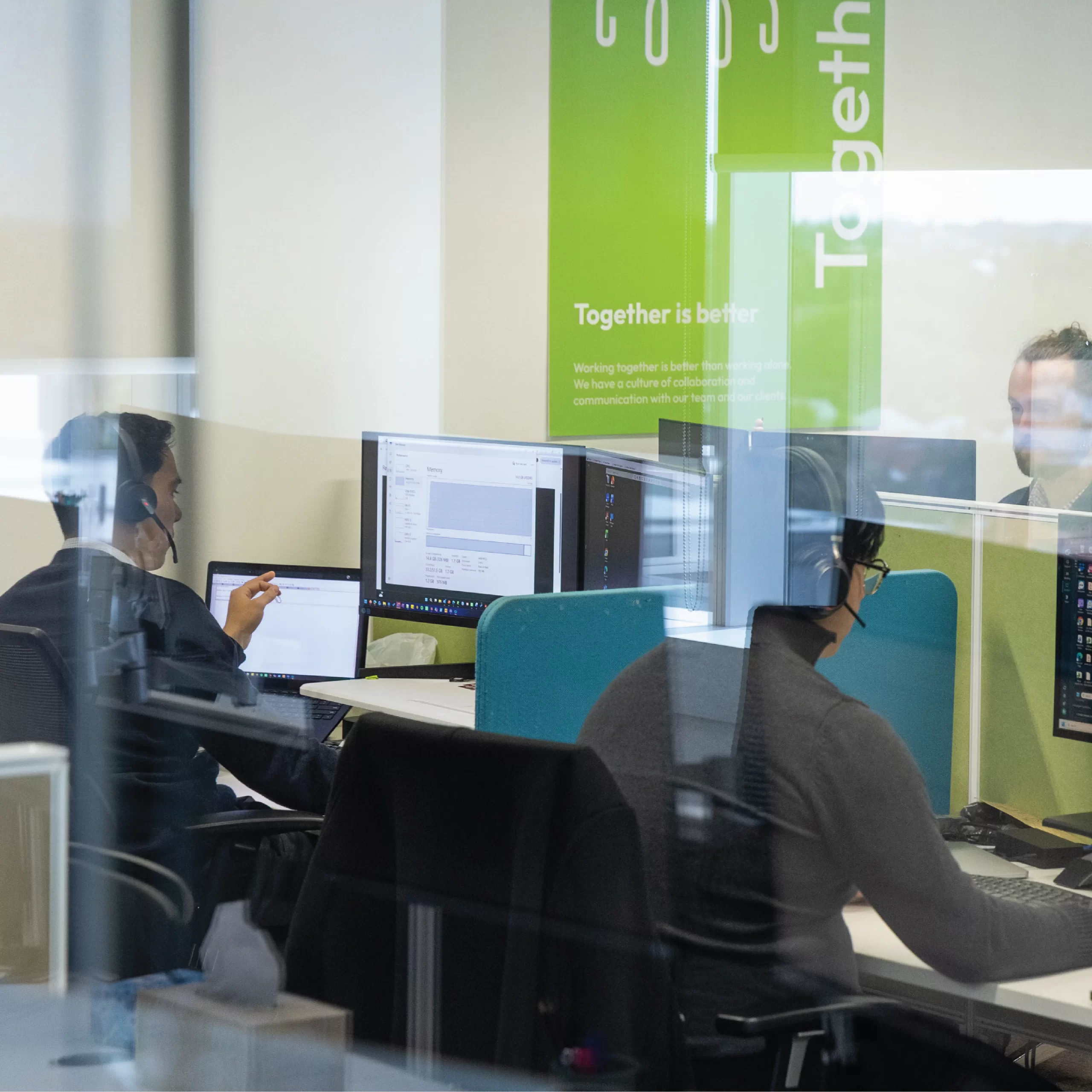 Looking into an IT support office space with workers at desks.