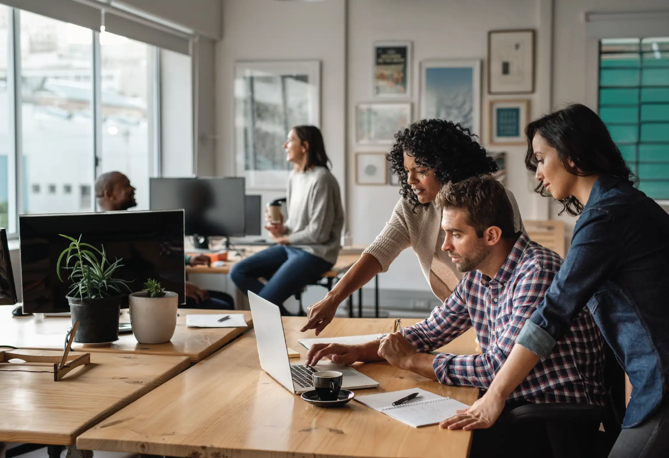 three people working at a computer together in an office environment