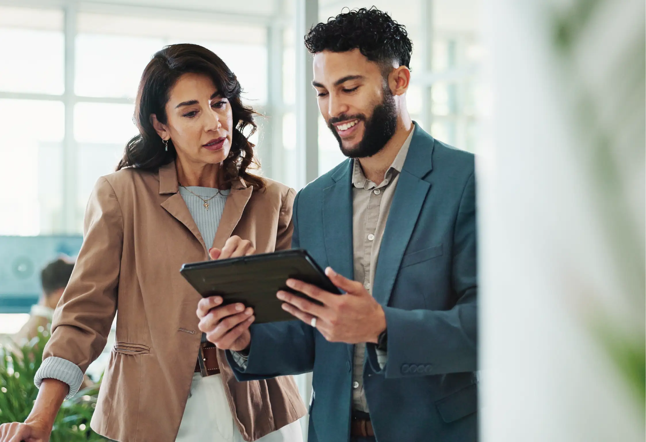 a woman and man both stadning and looking at an ipad